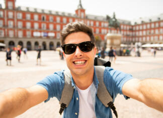 Svetovalnica: Študij v tujini Attractive young caucasian tourist student man having fun happy and excited taking a selfie with smart phone in Plaza Mayor, Madrid, Spain. Travel,vacation, holidays in European city concept.