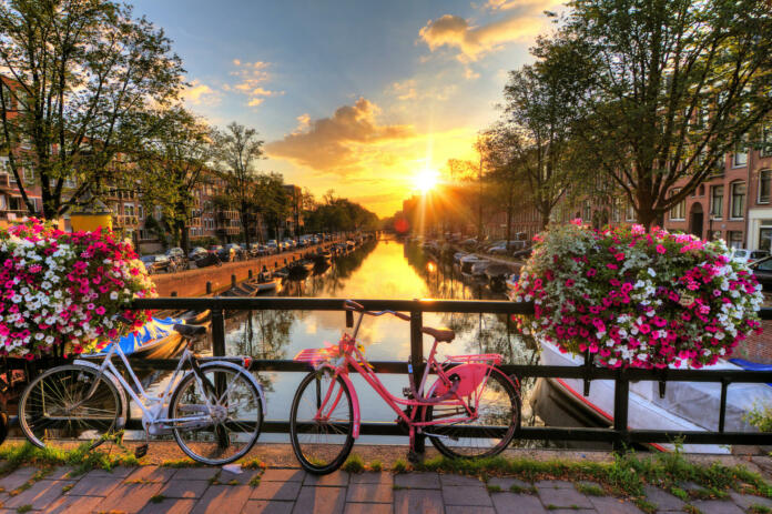 Beautiful sunrise over Amsterdam, The Netherlands, with flowers and bicycles on the bridge in spring