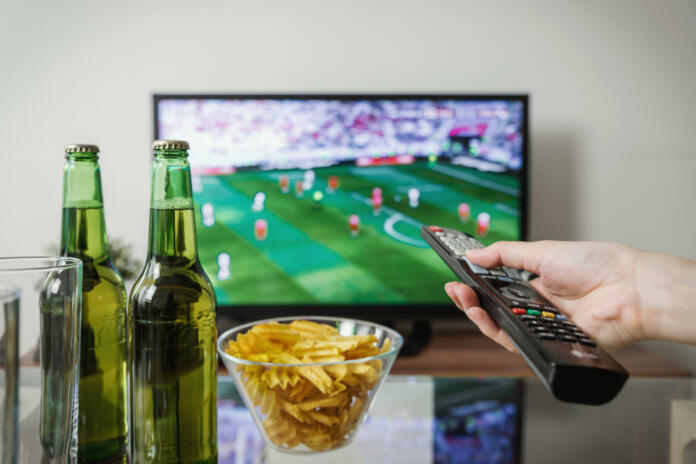 Televizija, na mizi čips in dve steklenici piva