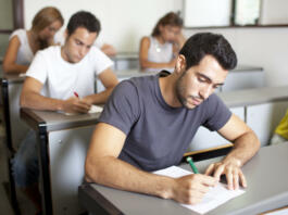 Good-looking male student writing an exam