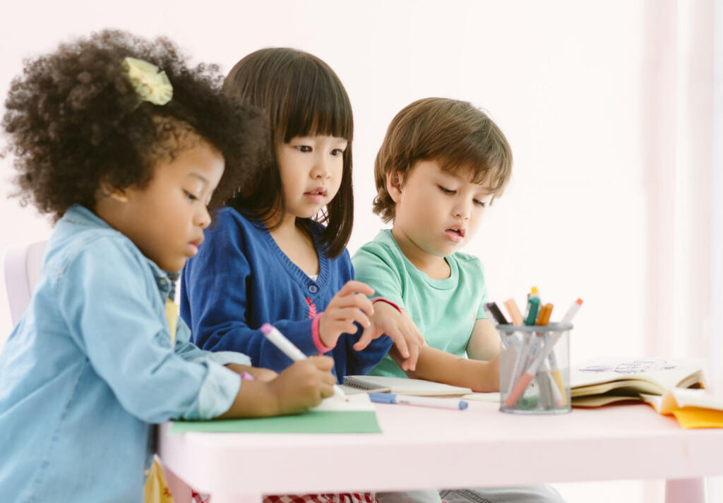 Group of diversity kids drawing and painting with crayon together with fun in art class at the kindergarten. Preschool international, education concept.