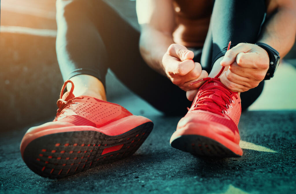 Man tying jogging shoes.He is running outdoors on a sunny day.