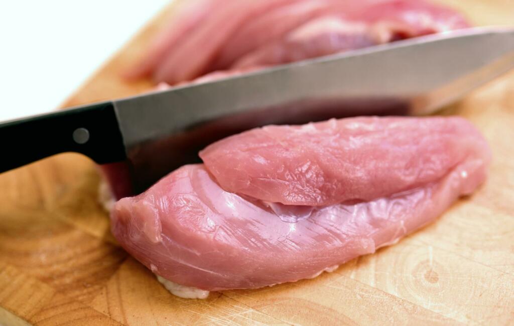 Piščančje meso na leseni deski in kuhinjski nož