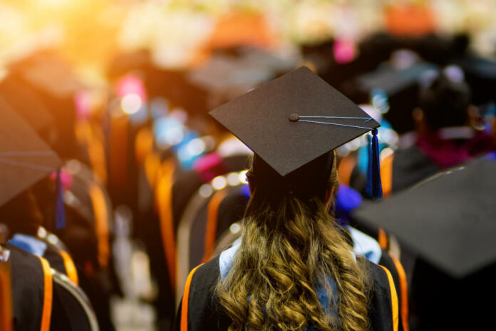 Rear view of the university graduates line up for degree award in the university graduation ceremony. The university graduates are gathering in the university graduation ceremony. Crowd of the graduates. Group of the graduates.