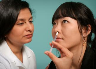 So spreji za nos rešitev za širjenje koronavirusa? Zdravnica vnaša cepivo v obliki spreja v levo nosnico ženske