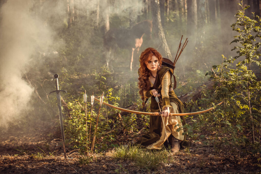 Warrior medieval woman with bow hunting in mystery forest
