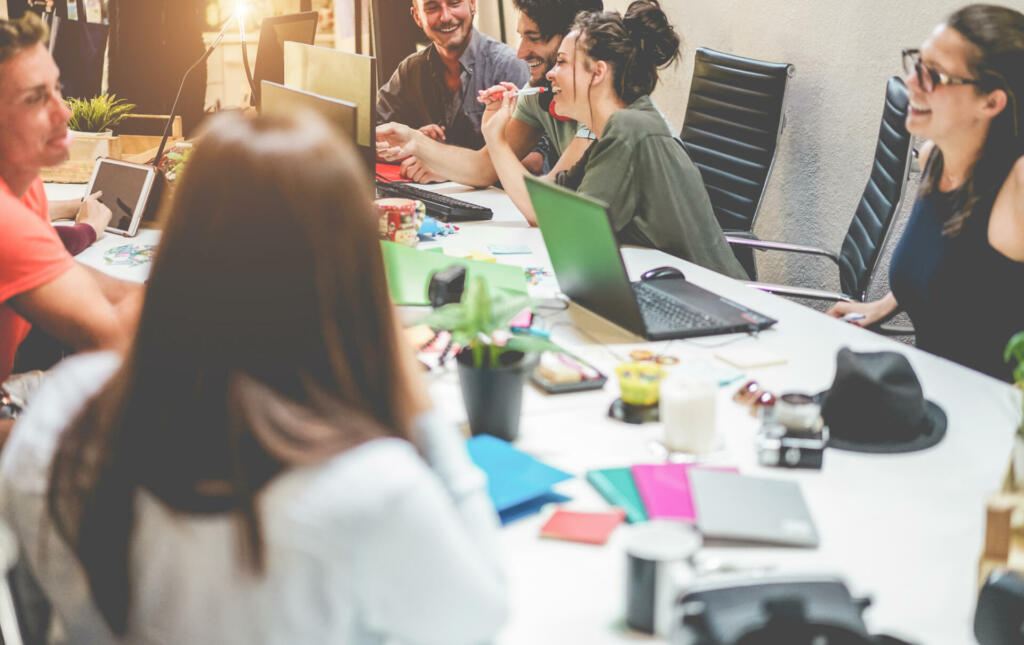 Young co-workers team talking during startup - Happy people planning a new project in creative workplace office - Focus on right top men - Technology, entrepreneur, marketing concept