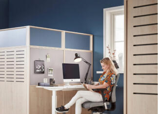 S prenosno predelno steno do zasebnosti Ženska za pisalno mizo ob pregradni steni