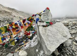 Everest se topi: Sledijo nove lokacije baz Everesta? Skala z napisom EVEREST BASE CAMP in pisane molilne zastavice