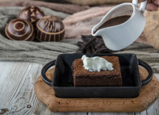 Spoznajte zgodbo o brownijih: kako so postali svetovna senzacija! sizzling chocolate brownie is a sweet dish made using scoop of ice-cream on top served with a generous pouring of melted chocolate. server hot. selective focus.