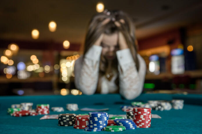 Upset woman in casino sitting behind poker table