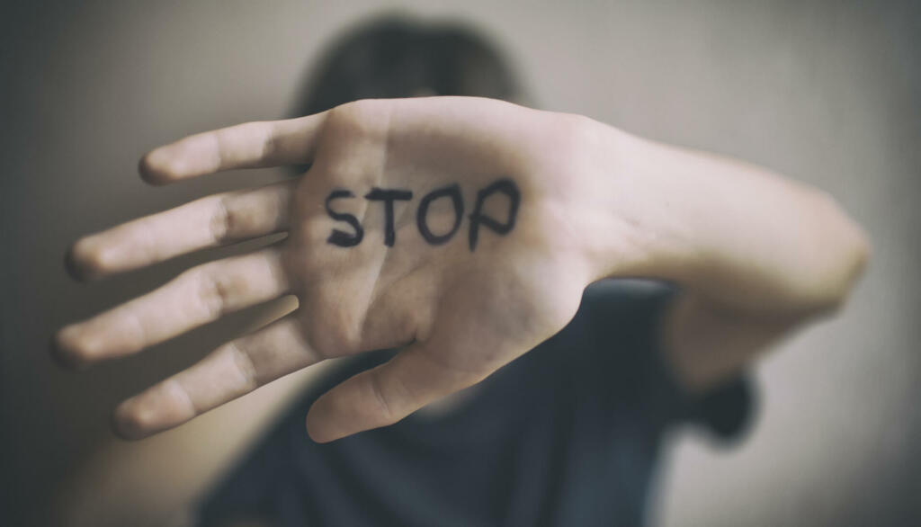 A 18-year-old guy protects himself with his hand with the inscription Stop isolated