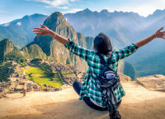 Neverjetna dežela Inkov in predinkovskih kultur A woman tourist contemplating the amazing landscape of Machu Picchu with arms open. Archaeological site, UNESCO World Heritage