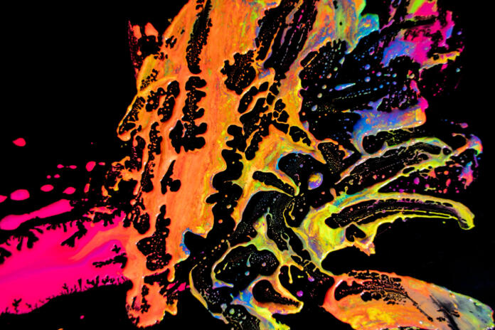 Abstract vibrant multi-color wet paint drops and splotch on black background. Bright orange and pink neon colors. Street art isolated