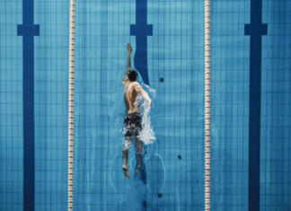 Nikoli ne reci nikoli in ne izpusti ponujene priložnosti! Aerial Top View Male Swimmer Swimming in Swimming Pool. Professional Athlete Training for the Championship, using Front Crawl, Freestyle Technique. Top View Shot
