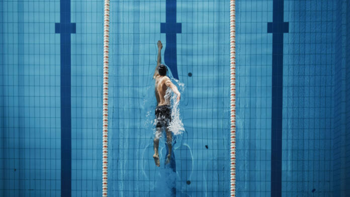 Aerial Top View Male Swimmer Swimming in Swimming Pool. Professional Athlete Training for the Championship, using Front Crawl, Freestyle Technique. Top View Shot
