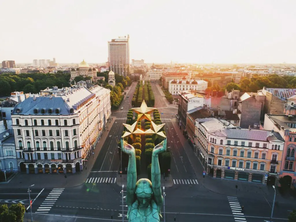 Kip, ki v rokah drži tri zlate zvezde in pogled na mestno ulico