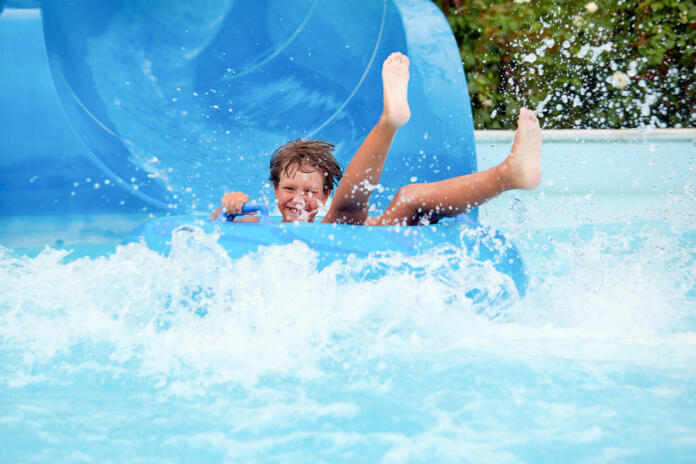 an 8 year old boy is riding in the water Park on inflatable circles on water slides.