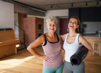 Bi imel fitnes kar doma? An active senior woman after workout training with adult daughter indoors at home, celebrating success.