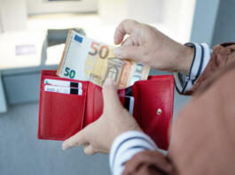 ATM machine and euros cash. Closeup of woman hand holding euro banknotes. Withdraw money from an ATM