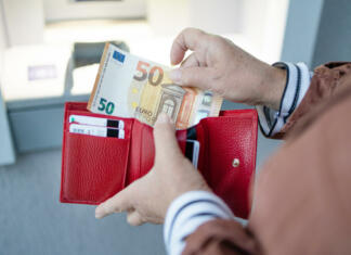 Evro sem, evro tja … ATM machine and euros cash. Closeup of woman hand holding euro banknotes. Withdraw money from an ATM