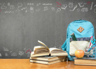 Ponavljanje, prepis, pavziranje ali morda vzporedno študiranje Back to school concept with school books, textbooks, backpack and stationery supplies on classroom desk with teacher's black chalkboard background with educational doodle for new academic year begin