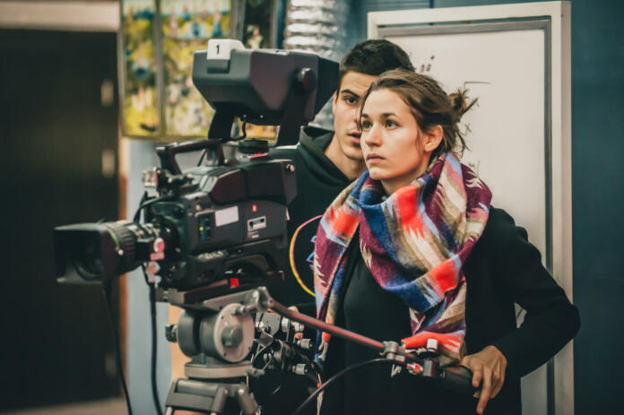 Behind the scene. Cameraman and assistant shooting the film scene with camera in film studio