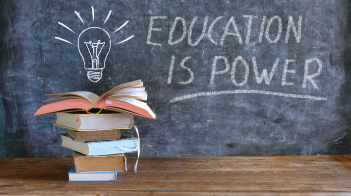 books and blackboard with drawing of a lightbulb and slogan education is power,learning,knowledge,back to school concept