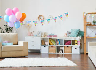 Zabava kar doma Bunch of colorful balloons and stack of giftboxes on armchair in the living-room decorated with flags for home birthday party