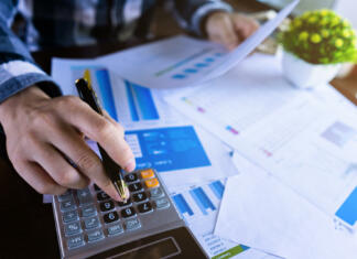ŠOU svetovalnica Close up businessman using calculator and reading paper document about business data, accountancy document, graph profit company.