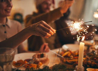 Domača silvestrska večerja Close up of hand holding sparkler over Christmas dinner background, copy space