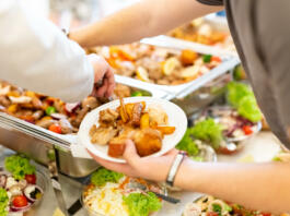 Close up of man hand holding plate with buffet catering food. Celebration and meal concept.