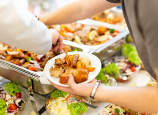 Končno bom dobil študentske bone! Close up of man hand holding plate with buffet catering food. Celebration and meal concept.