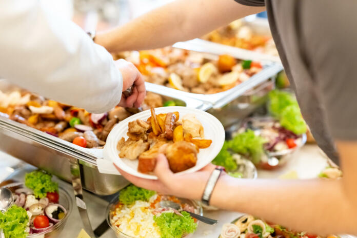 Close up of man hand holding plate with buffet catering food. Celebration and meal concept.
