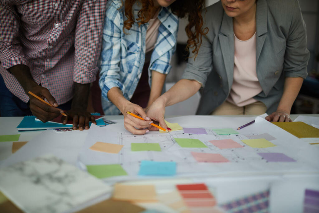 Closeup of creative business team working on design project focus on table with roadmap and colorful stickie notes, copy space