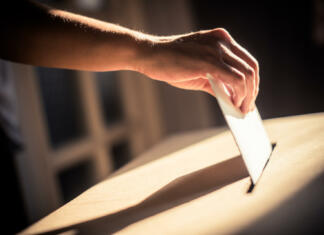 Fizično obračunavanje na študentskih volitvah Conceptual image of a person voting, casting a ballot at a polling station, during elections.