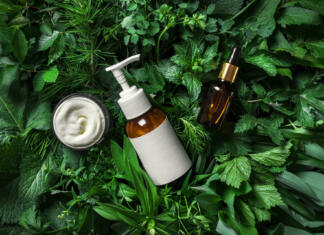 Naravna kozmetika Cosmetic skin care products (body lotion, hair shampoo, face creme, essencial oil, serum) on green leaves as background, top view. Natural eco beauty and organic green skin care concept.