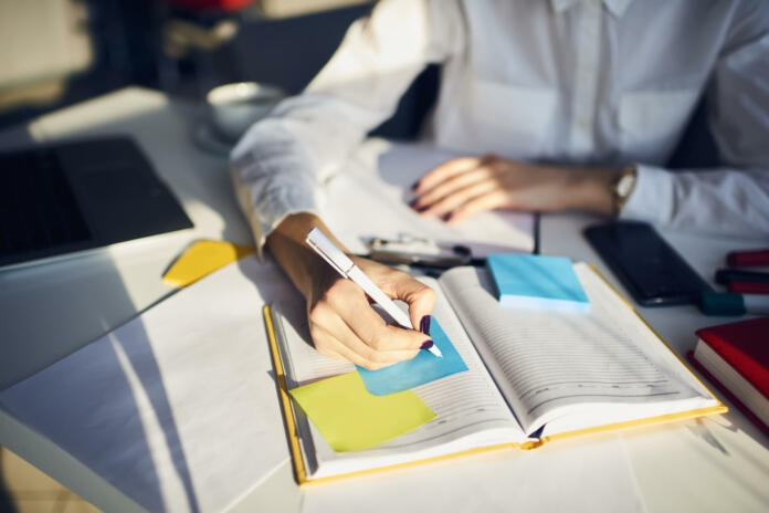 Cropped image of creative female secretary creating planning for executive noting important meeting and events organizing work of busy boss while sitting at working place in coworking office