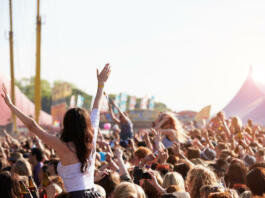 Crowds Enjoying Themselves At Outdoor Music Festival With Arms in The Air
