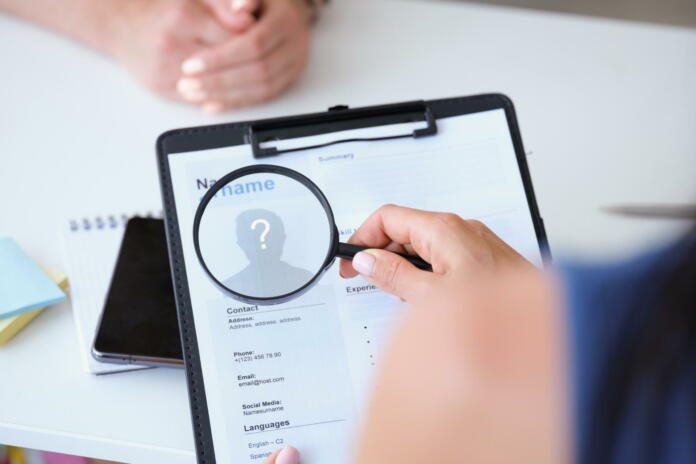 Employer looking at worker resume with magnifying glass closeup. Recruitment concept