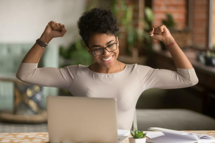 Excited happy african american woman feeling winner rejoicing online win got new job opportunity, overjoyed motivated mixed race girl student receive good test results on laptop celebrating admission