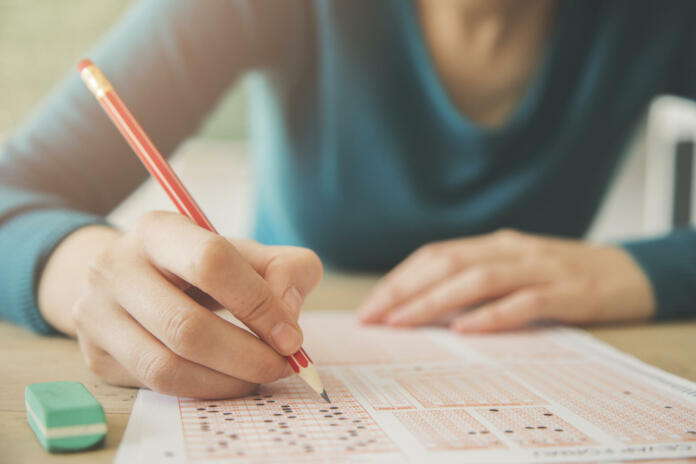 Female student holding pencil and examination paper