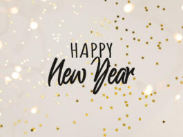 Festive gold background with Happy New Year celebration. Shining stars confetti and fairy lights on beige background. Flat lay, top view.