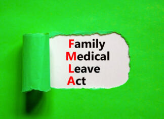 Denarni prejemki študentskih družin FMLA family medical leave act symbol. Concept words FMLA family medical leave act on wooden cubes on on beautiful green background. Businessman hand. Medical FMLA family medical leave act concept.