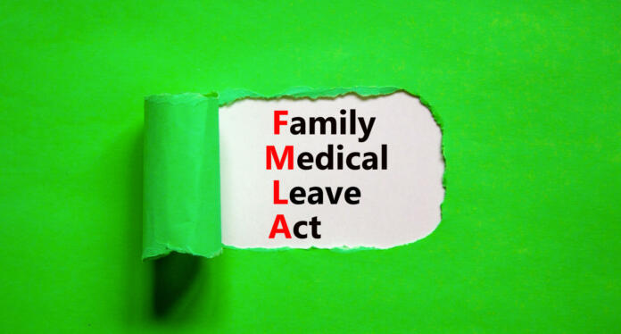 FMLA family medical leave act symbol. Concept words FMLA family medical leave act on wooden cubes on on beautiful green background. Businessman hand. Medical FMLA family medical leave act concept.