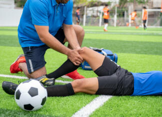 Tekaške poškodbe Footballer wearing a blue shirt, black pants injured in the lawn during the race.