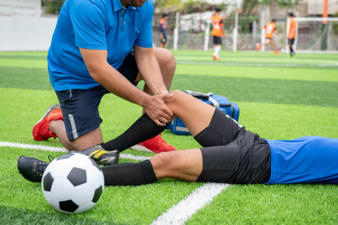Footballer wearing a blue shirt, black pants injured in the lawn during the race.