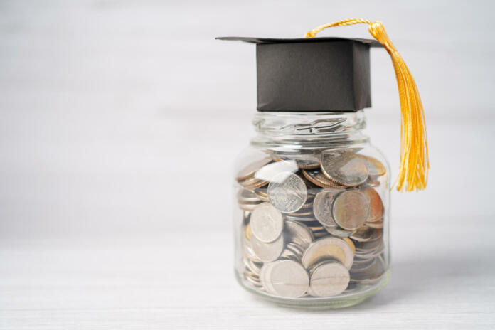 Graduation gap hat on coins money in jar for education fund; study learning concept.