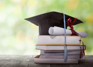 Študenti so za večji nadzor Graduation hat with degree paper on a stack of book against blurred background