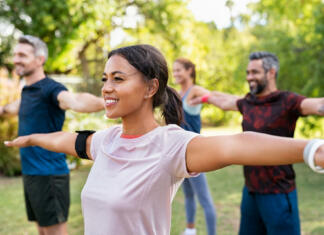 Naporni trening Group of multiethnic mature people stretching arms outdoor. Middle aged yoga class doing breathing exercise at park. Beautifil women and fit men doing breath exercise together with outstretched arms.